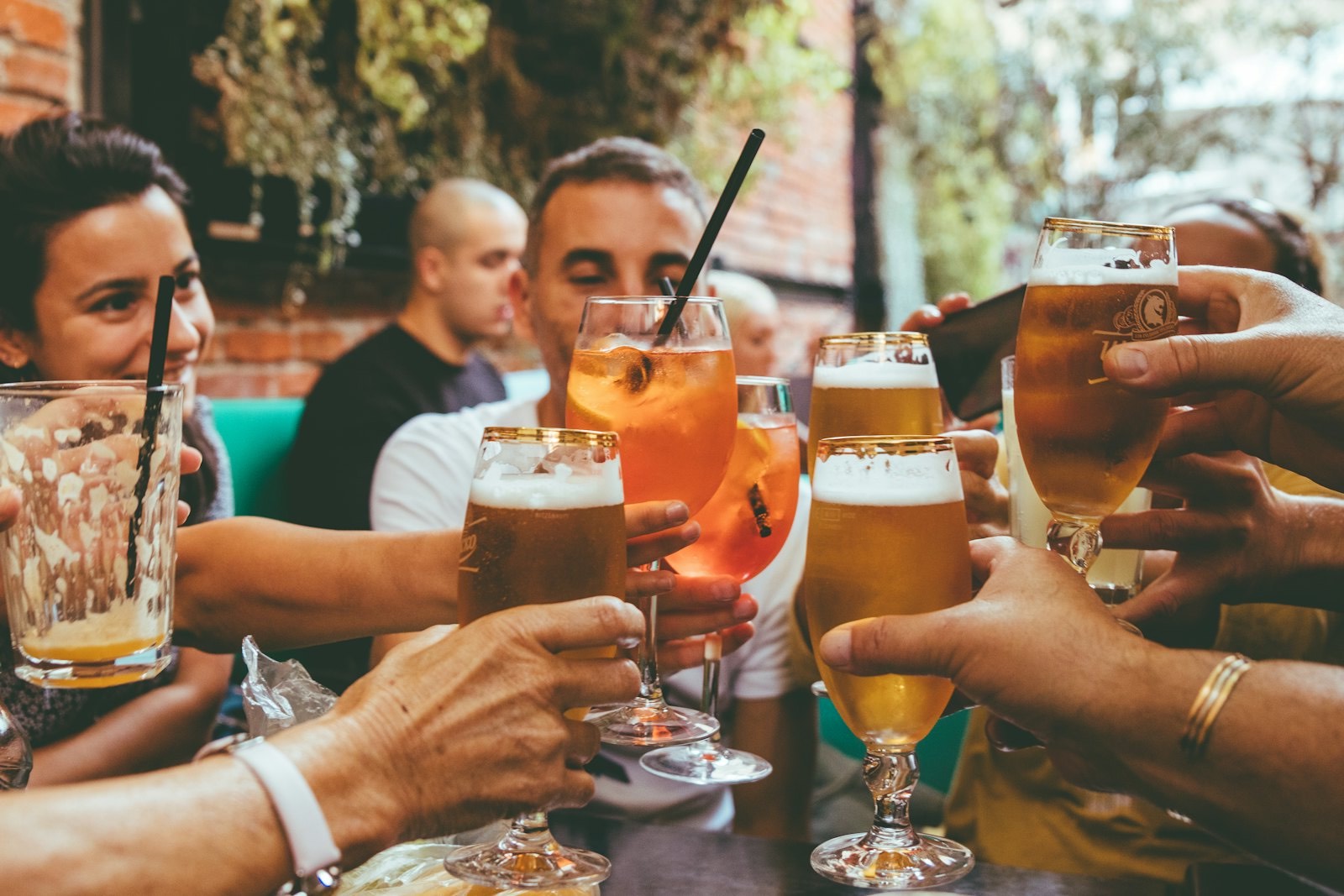 A group of friends clinking glasses of beer and cocktails at a pub table